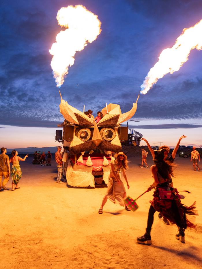 The Kuker at dusk on the playa, horns firing, dancers in the foreground